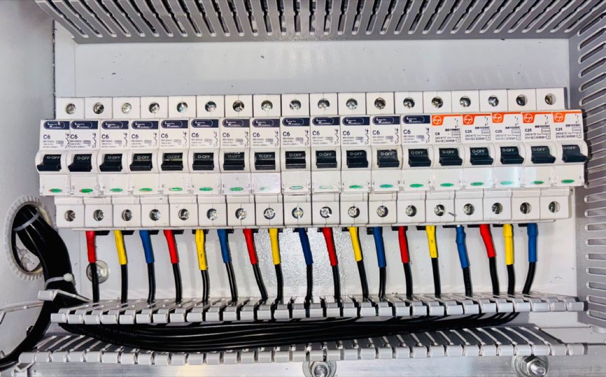 Close-up of a residential circuit breaker panel with color-coded wiring - a 36 kW electric tankless water heater requires 3-4 dedicated double-pole breakers and 150 amps of available service