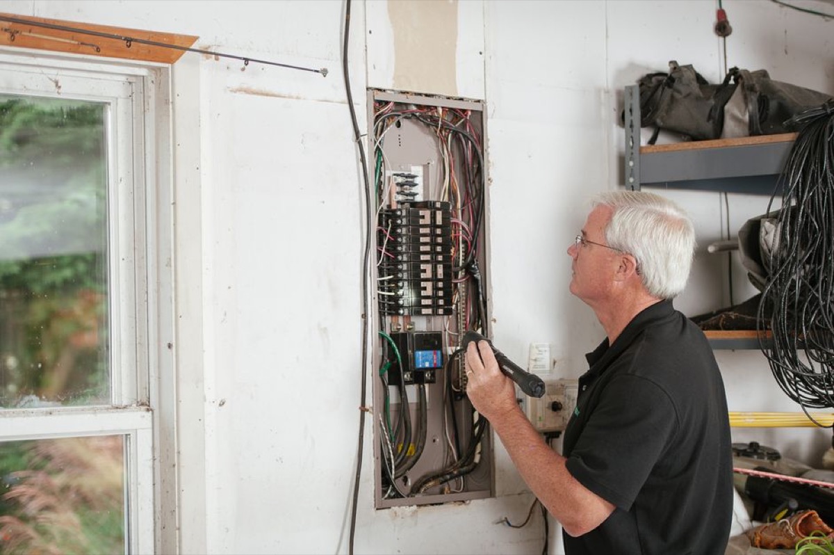 Electrician inspecting a residential electrical panel to assess capacity for a whole-house electric tankless water heater installation - a required step before purchasing any 36 kW unit