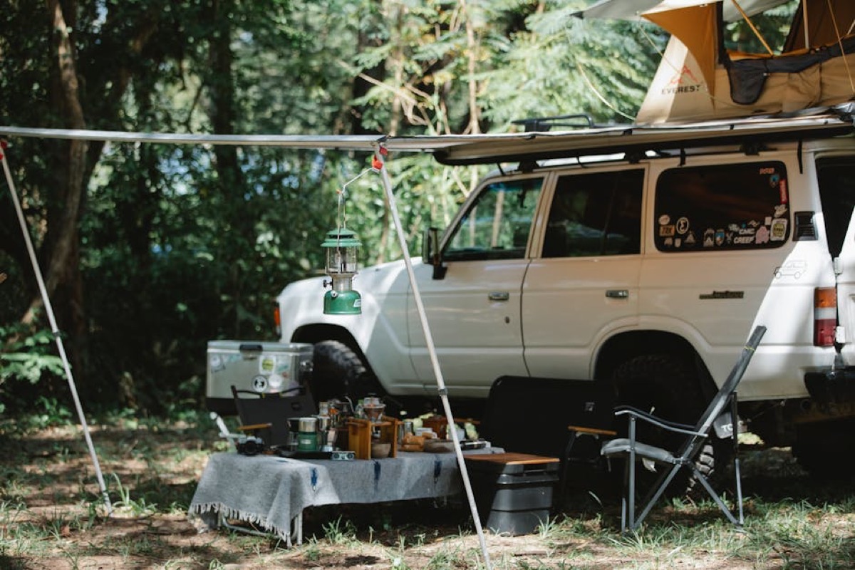 Outdoor camping stove setup in a rural field, demonstrating portable propane equipment for off-grid hot water and cooking