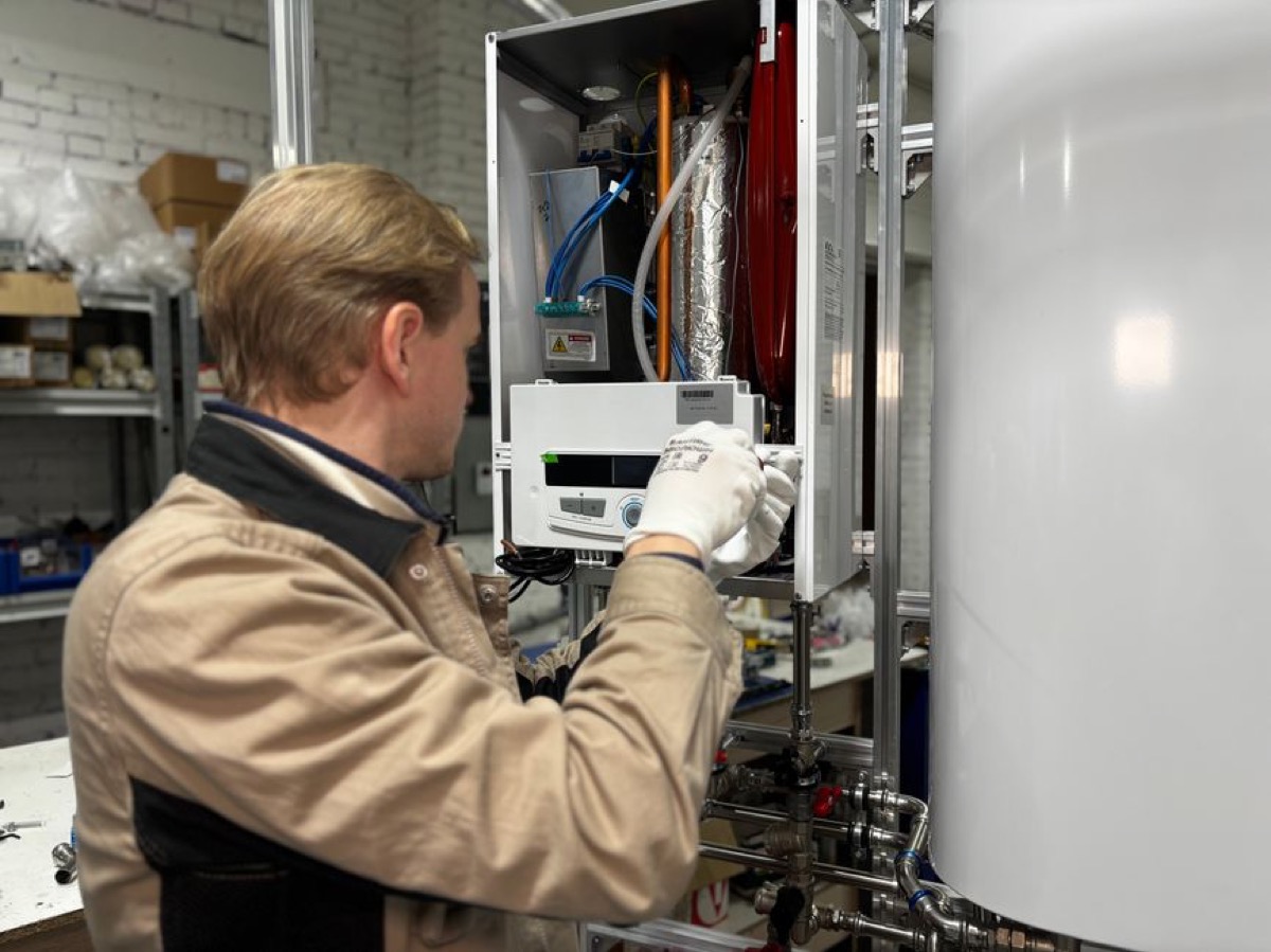Technician servicing a heat pump water heater unit showing internal components and refrigerant connections