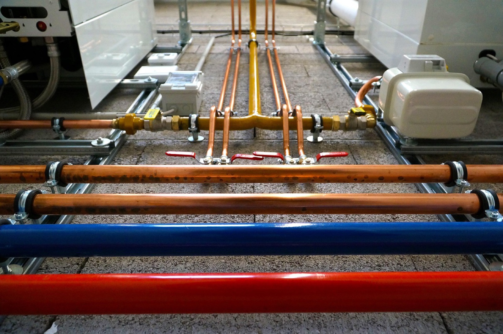 Tankless water heater plumbing installation showing professional wall-mounted unit with modern copper piping