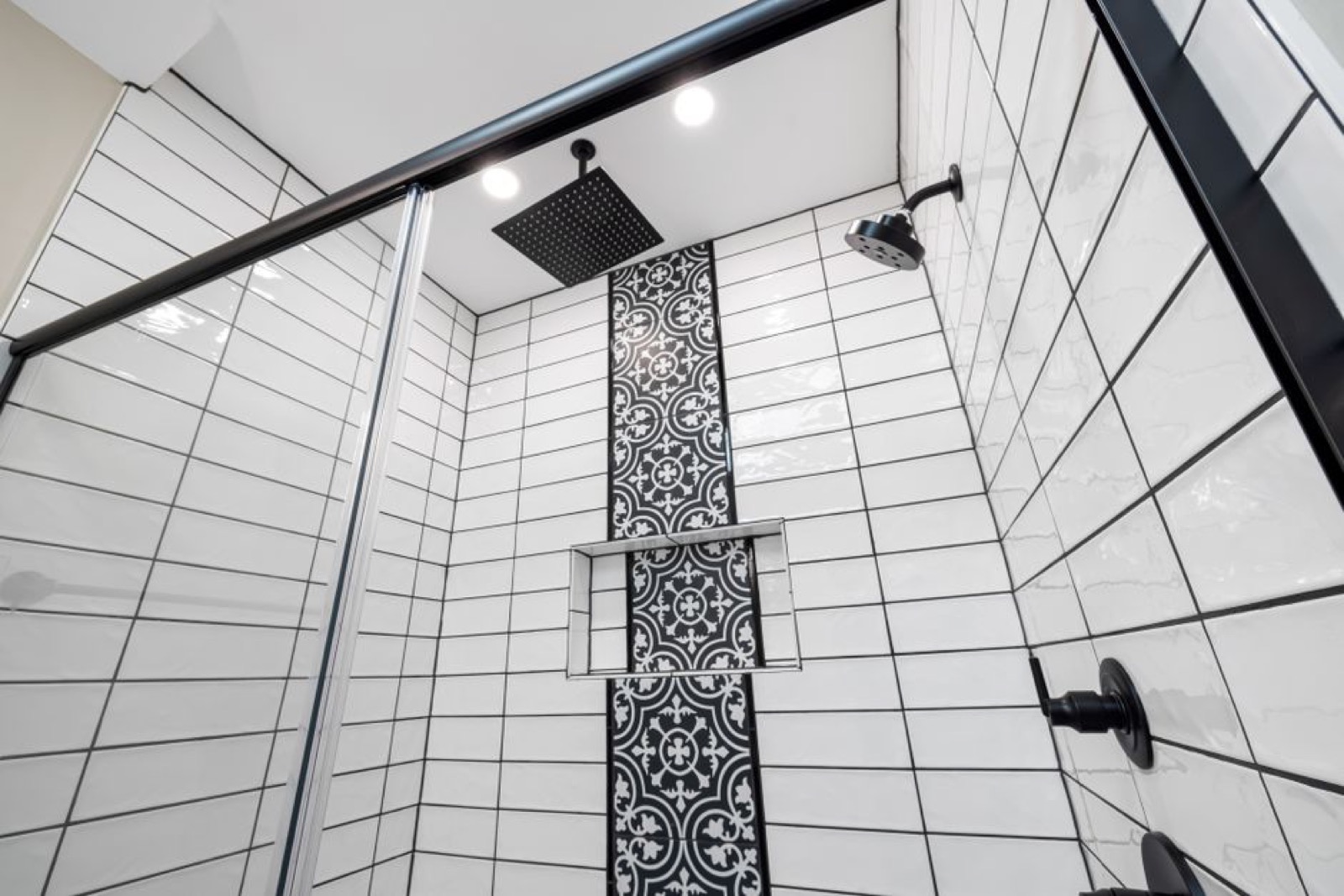 Modern bathroom shower with dual shower heads and visible thermostatic control valve, illustrating a multi-fixture tankless setup