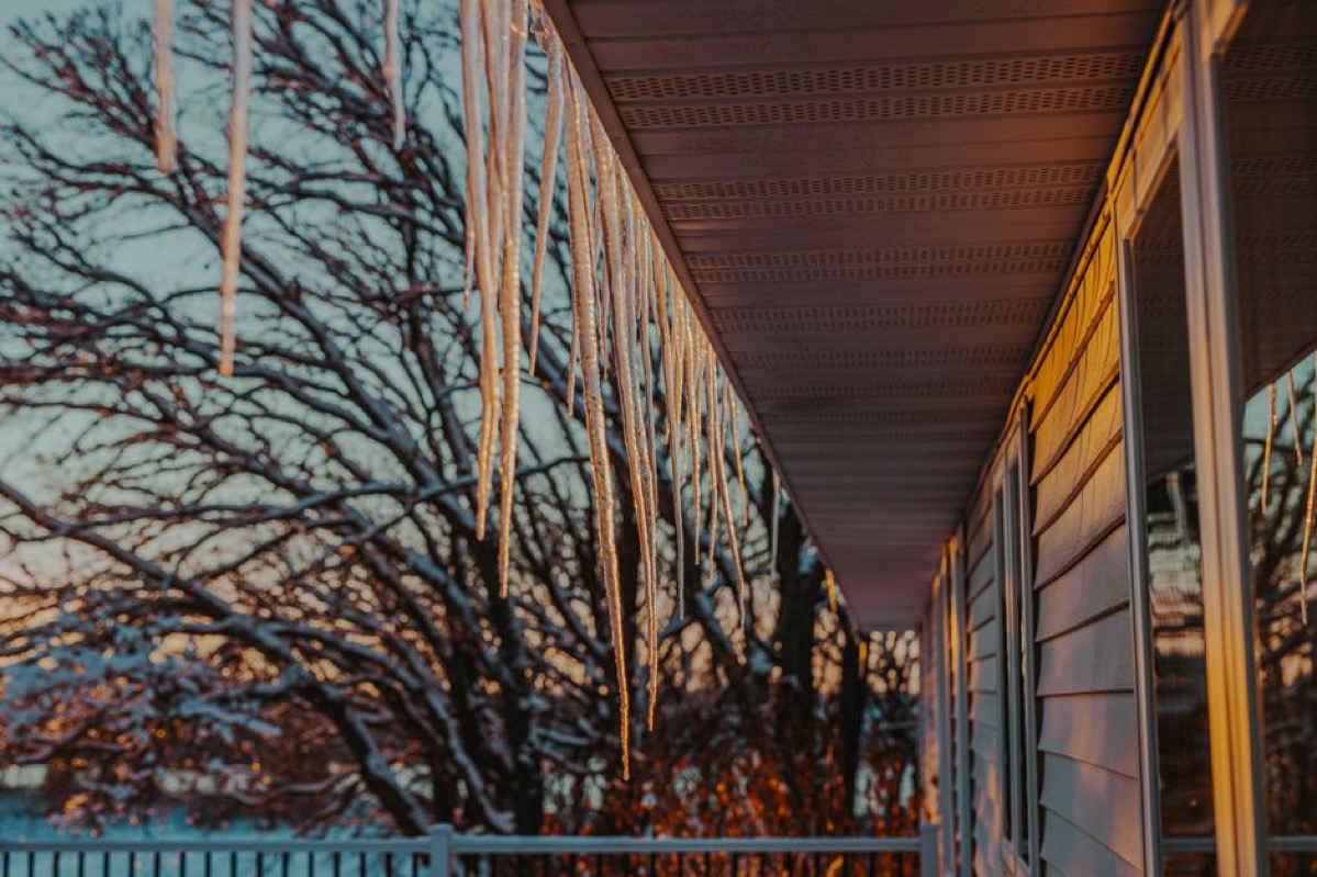 Icicles hanging from a roof eave in winter, illustrating the freezing temperatures that damage unprotected tankless water heater pipes