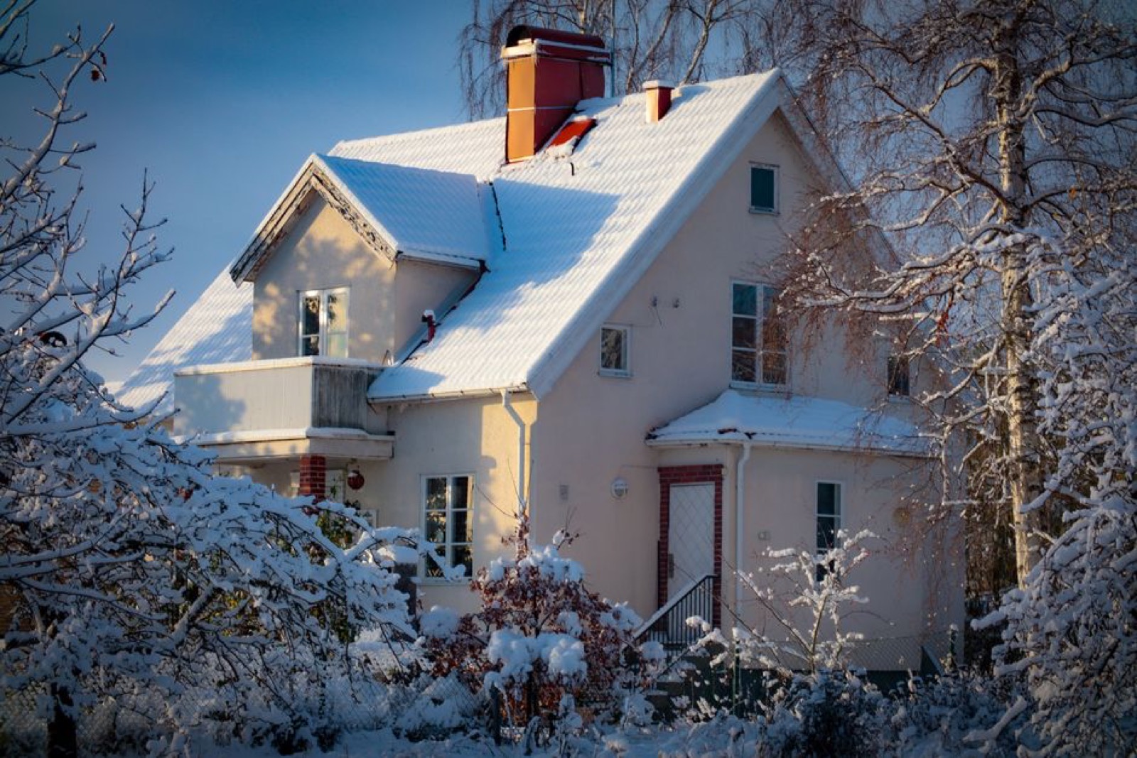 Snow-covered home exterior in winter, illustrating cold climate freeze risk for outdoor tankless water heaters